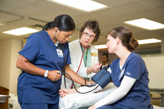 UM-Flint nursing students learning medical technique from faculty member.