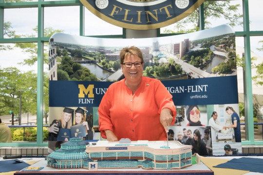 Chancellor Susan E. Borrego cuts a cake shaped as a replica of UM-Flint’s University Pavilion.