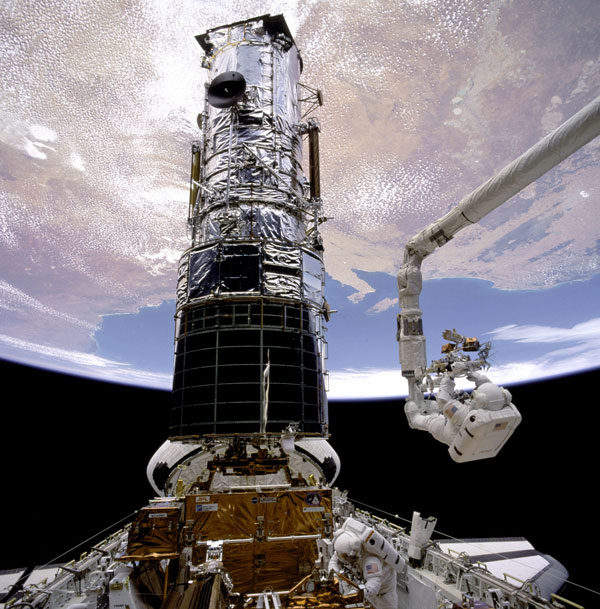 Story Musgrave helping to repair Hubble Telescope.