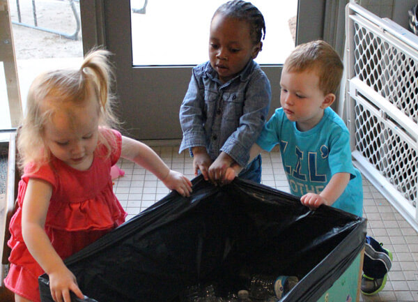 ECDC children maneuver a box of empty water bottles for their project.