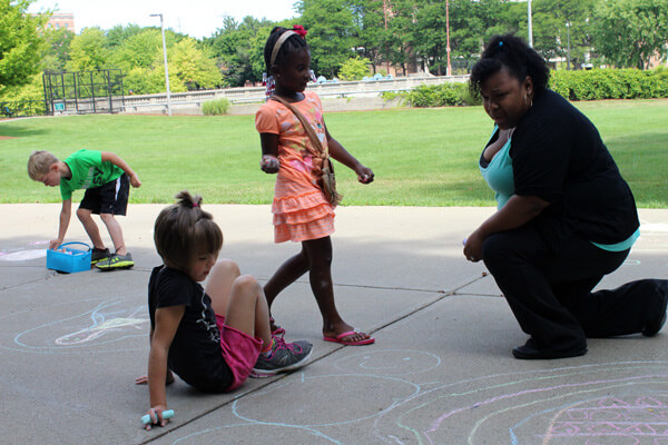 UM-Flint Graduate student Starletta Rett-Henry uses a chalk activity with kids to spark ideas.