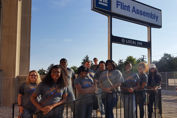 Skye Whitcomb (far left) stands with her Flint Southwestern high school students outside GM'S Flint Assembly Plant.