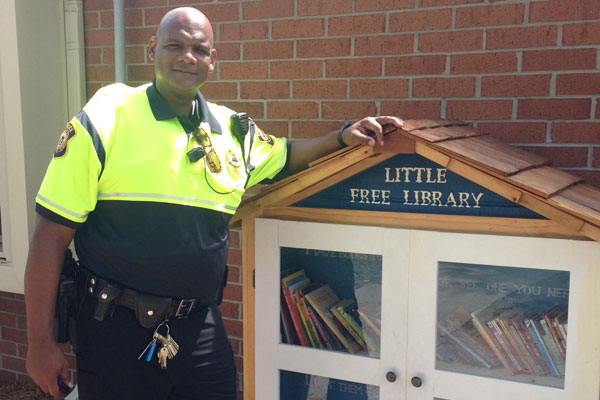 UM-Flint public safety office Mark Walker stands near DPS' new Little Free Library.