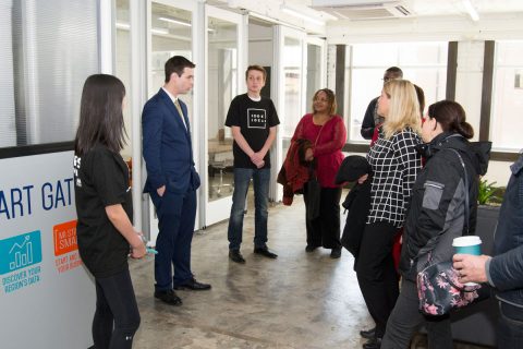 Nic Custer from UM-Flint's Innovation Incubator talks with attendees at the ribbon-cutting ceremony.