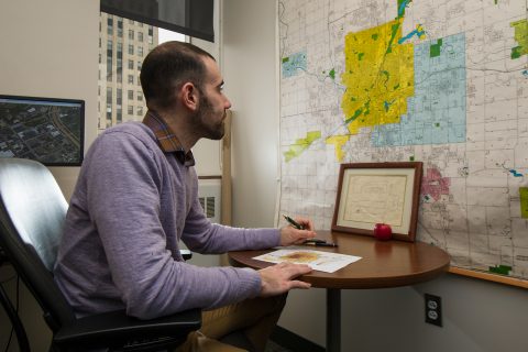 Richard Sadler, in his office, referencing map of Flint and Genesee County.