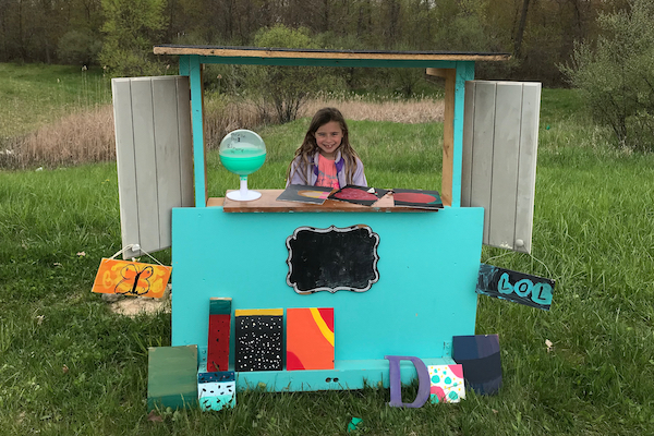 A third-grade girl sells artwork at her art stand.