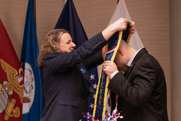 Helen Budd places stole on on graduate at Veterans' Graduation Dinner. (Photo by UM-Flint)