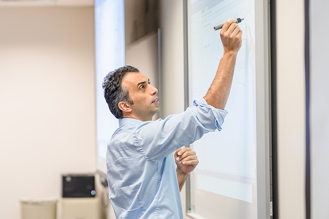 Dr. HaliDr. Halil Bisgin has used his artificial intelligence expertise in collaborations with the FDA and the Beaumont Health System. (Photo by UM-Flint) l Bisgin writAssistant Professor of Computer Science has used his artificial intelligence expertise in collaborations with the FDA and the Beaumont Health System. (Photo by UM-Flint) ing on a whiteboard