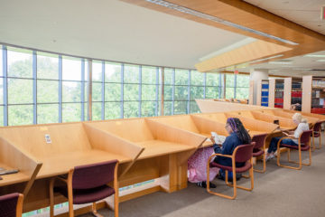 Three students study at desks in UM-Flint's Thompson Library.