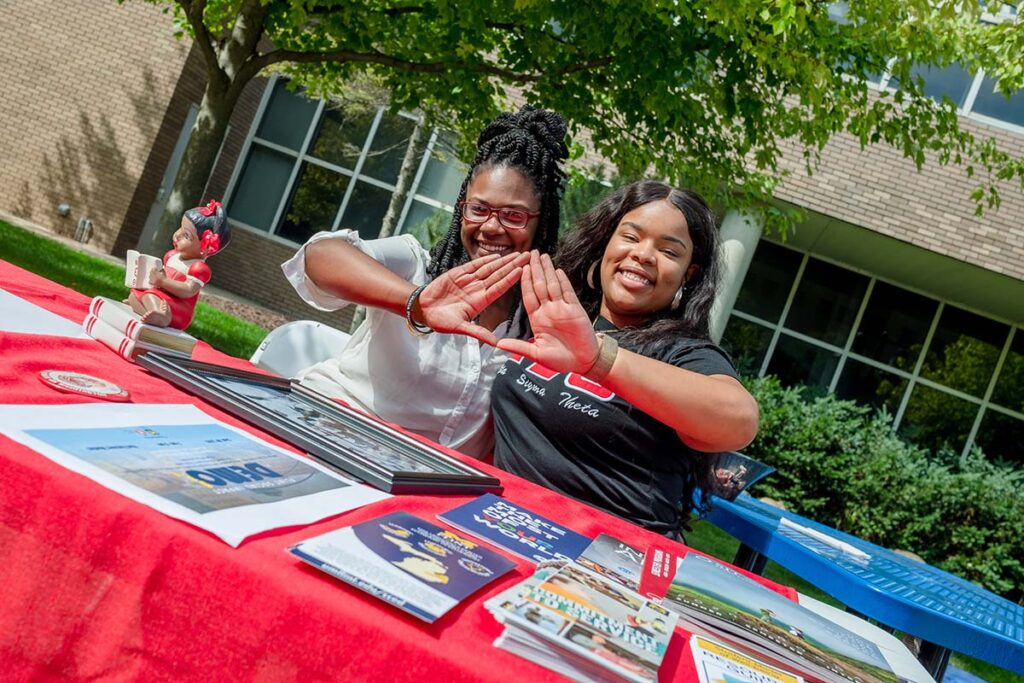 two female students displaying a greek life hand sign