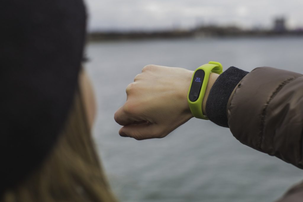 A woman looking at a fitness tracker on her wrist. 