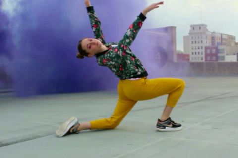 Meredith Sheatzley dancing on a rooftop with colored smoke behind her