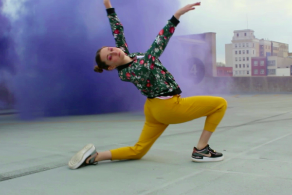 Meredith Sheatzley dancing on a rooftop with colored smoke behind her