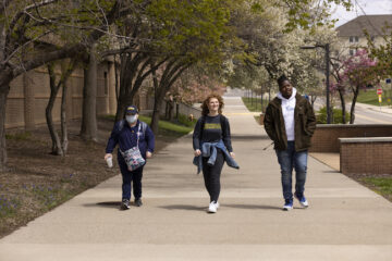 Three UM-Flint students walk along a sidewalk on campus.