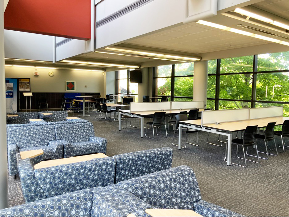 Chairs and tables with a window showing campus greenery. 