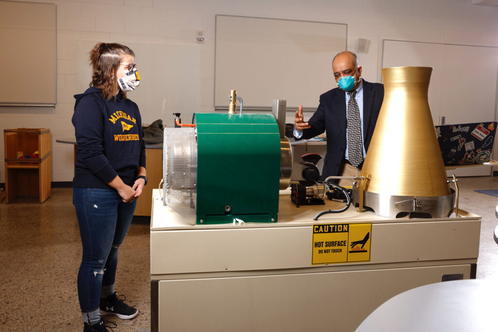 Student and professor looking at a piece of equipment. 