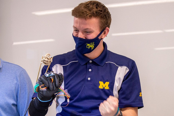 A student using a glove chopstick invention