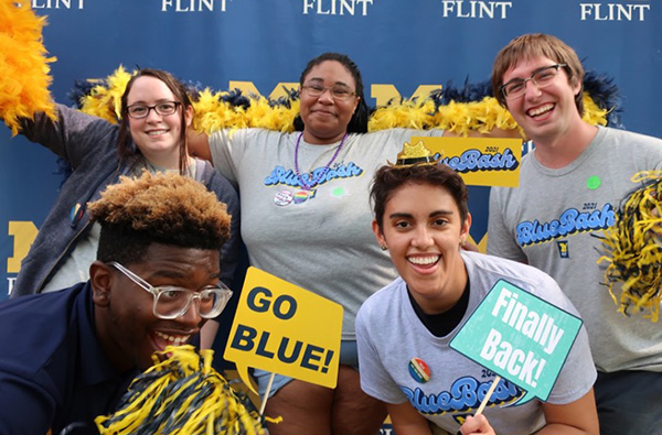 Harley with friends in front of a UM-Flint logo wall