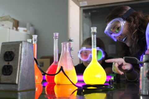 Chemistry student observes beakers with bright liquids