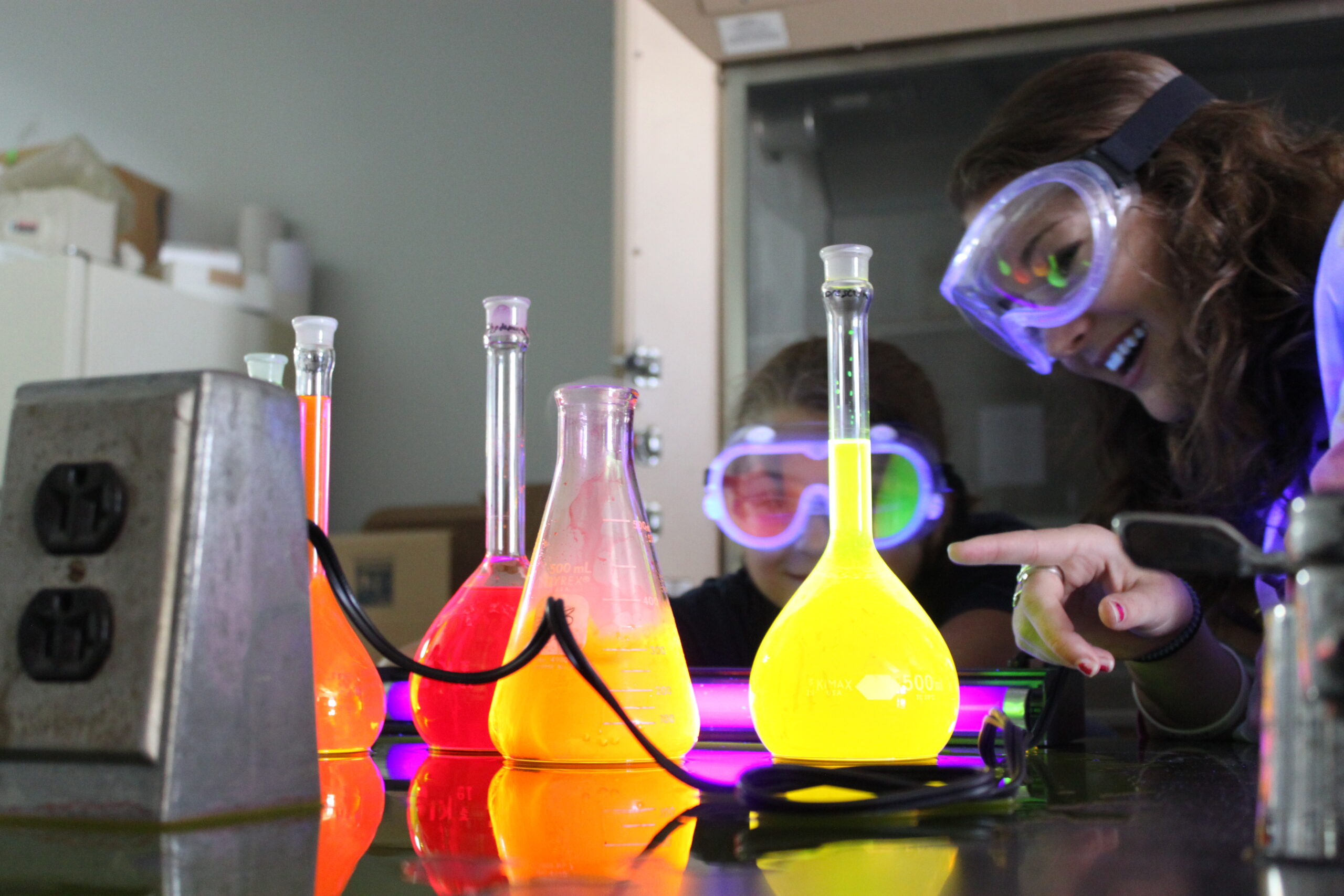 Chemistry student observes beakers with bright liquids