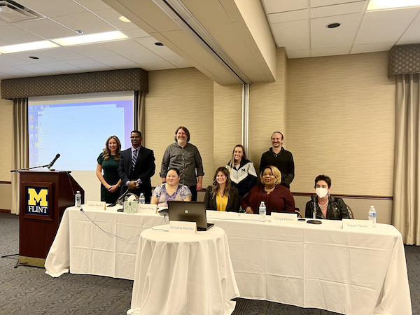 In-person members of the Crip Camp planning team and student panel post for a picture at a long table after the event. 