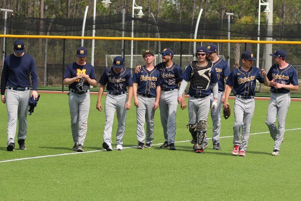 UM-Flint baseball team members walking on the field. 