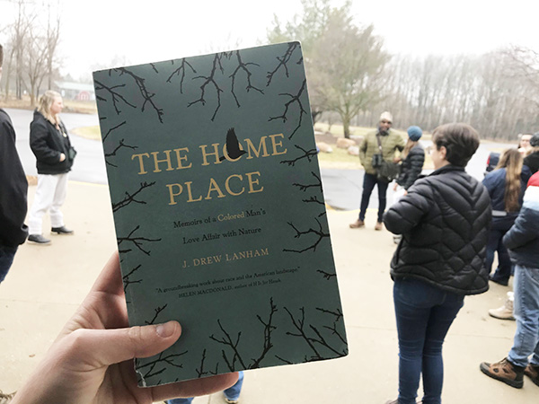 Hand holding up the paper copy of The Home Place: Memoirs of a Colored Man's Love Affair with Nature at Formar Nature Preserve 