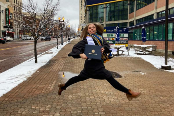 Mallory leaping in the air with her diploma