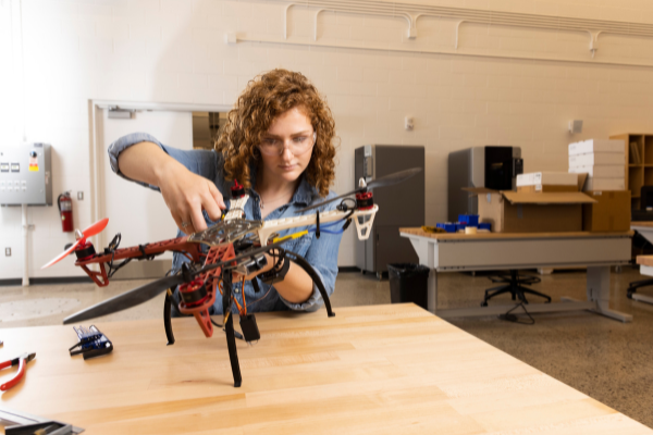 A female student in a workshop building a drone. 