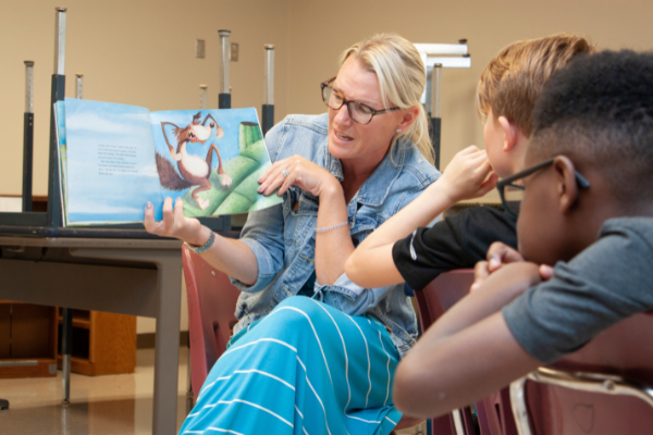 An instructor reading a book aloud to students. 