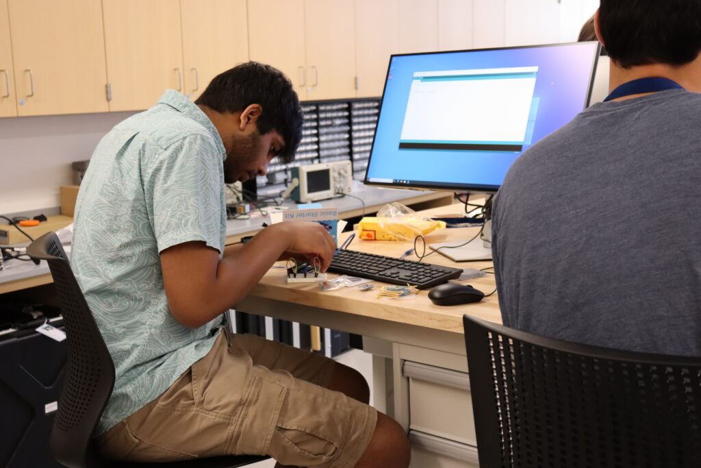 A student working on a Arduino device at a desk. 