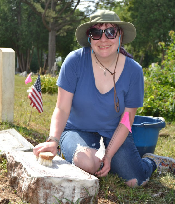 Senior Wendy Kimberly pauses from cleaning a headstone to post for a photo at Old Calvary Catholic Church. (Photo Credit: Madeline Campbell) 