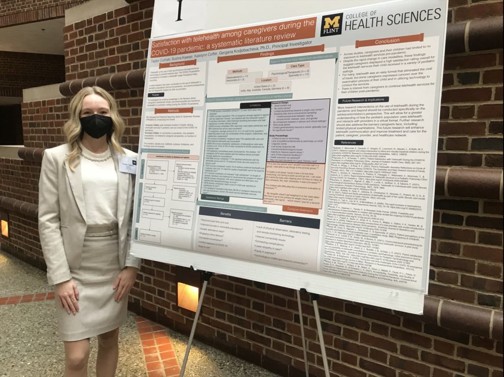 Culinski poses in front of presentation board at the Undergraduate Research Symposium in Ann Arbor