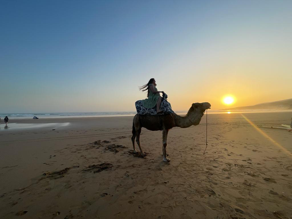 Yuliia Lane riding a camel by the seaside during sunset. 