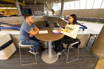 Two UM-Flint students speaking at a table.