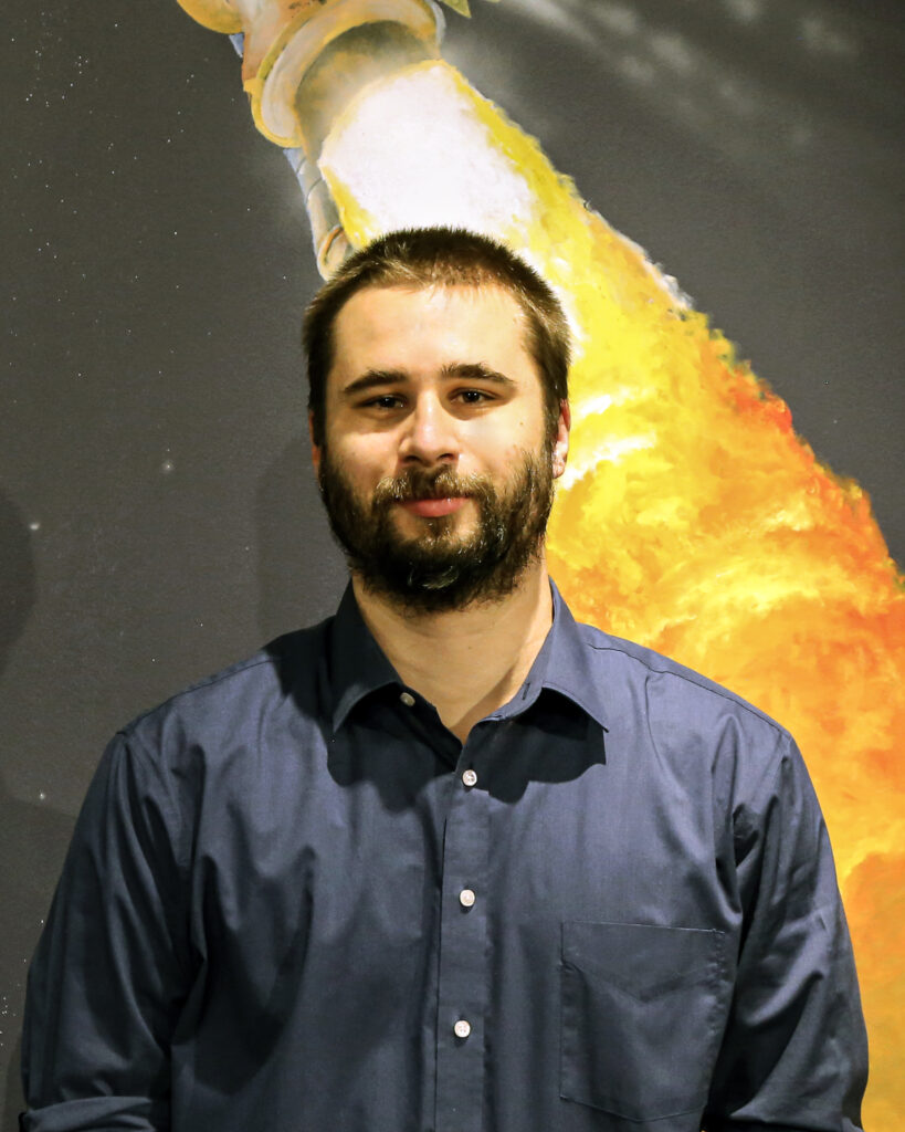 Patrick Ross standing in front of a photo of a rocket. 