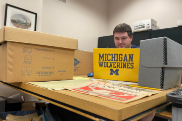 UM-Flint history student Michael Laskowski working in the archives on a laptop.