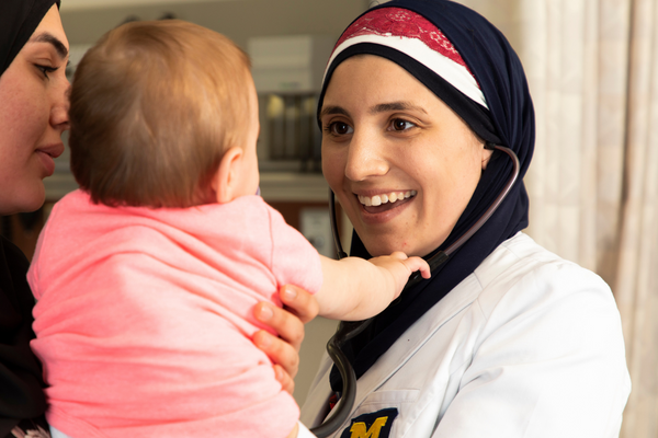 Two UM-Flint nursing students care for a small baby.