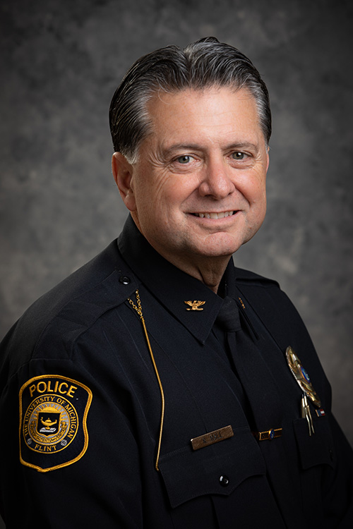 Portrait Photograph of Ray Hall, wearing a police uniform in front of a gray background.