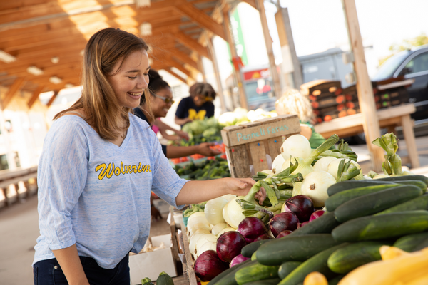 A UM-Flint student looks at produce at the Flint Farmer's Market.