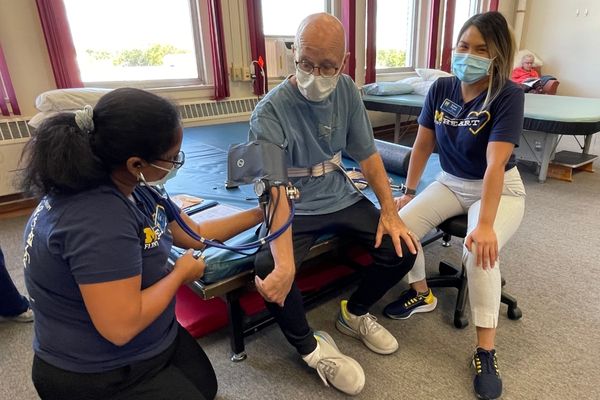 Two UM-Flint students taking the blood pressure of a patient at HEART. 