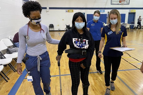 Two UM-Flint students assisting a patient with walking