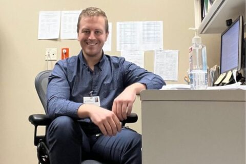 UM-Flint alumni Garrett Knickerbocker sits at his desk