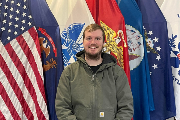 Christopher Mayes standing in front of flags