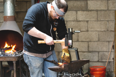 Man pounding metal on an anvil at Factory Two