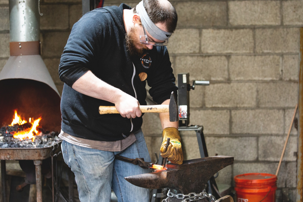 Man pounding metal on an anvil at Factory Two