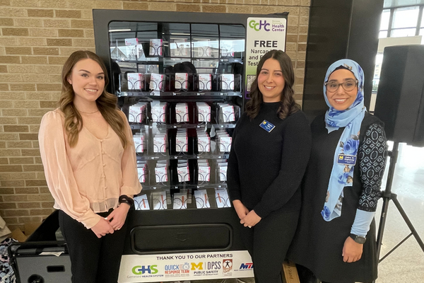 UM-Flint students Emily Barrie (left), Lauren Allen and Zehra Alghazaly pose with the Narcan vending machine they helped bring to downtown Flint.