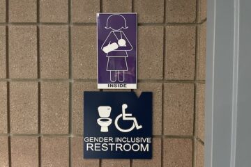 A gender inclusive restroom sign and a graphic of a person breast-feeding to note the restroom has a lactation room at UM-Flint.