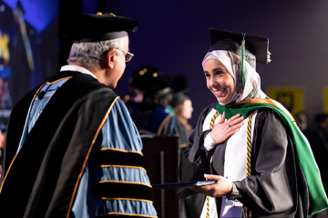 A student receiving her diploma on stage