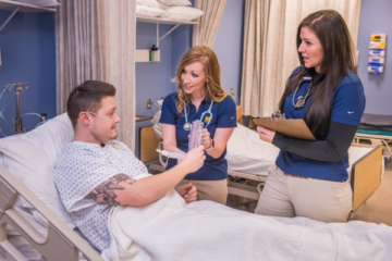 Two health care workers work with a patient